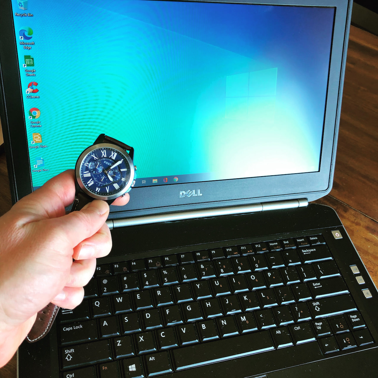 A repaired Dell laptop starting quickly beside a wristwatch